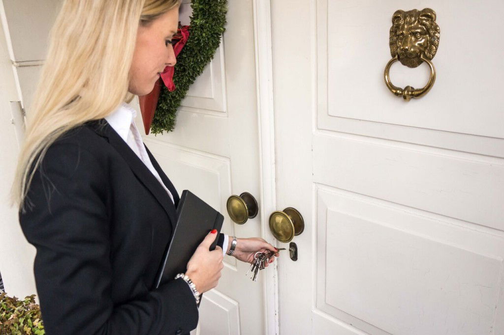 Frau Filusch öffnet eine repräsentative Tür, lächelt leicht und vermittelt Vertrauen und Kompetenz bei der Vermietung und dem Verkauf von Privat- und Gewerbeimmobilien